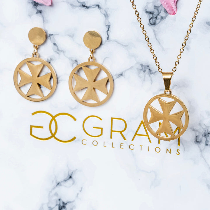 A set of gold-colored stainless steel jewelry including a necklace, a pendant, and a pair of earrings with a Maltese cross design, displayed on a marble surface.