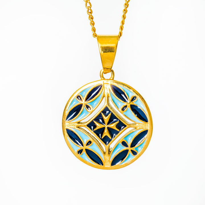 Gold Malta neckalce's pendant with blue and white design on a white background