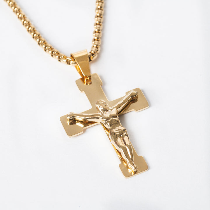 A close up view of gold colour necklace with cross pendant with icon of Jesus Christ. 