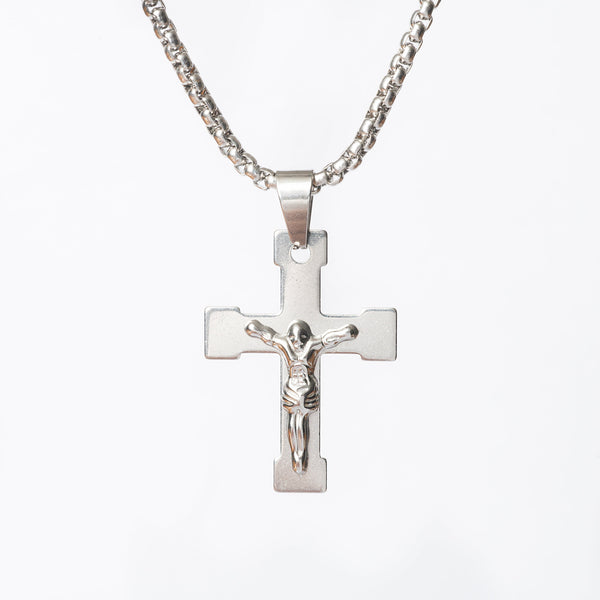 A close up view of Manly Cross Silver Necklace standing in the center of the image against a white background. 