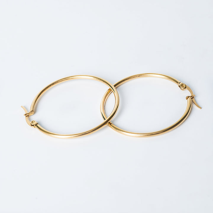 Gold Marcon hoop earrings with a smooth polished finish shown overlapping on a white background