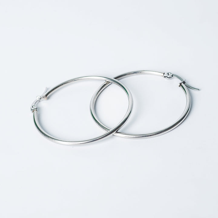 Silver Marcon hoop earrings with a smooth polished finish shown overlapping on a white background