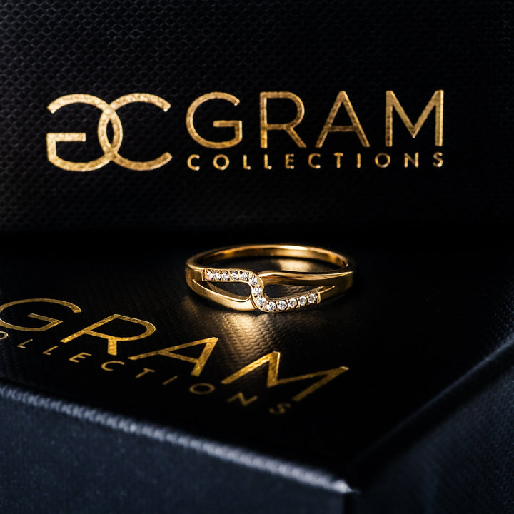 Marianne Gold Ring standing in the center of the image placed on its uniquely designed box. 