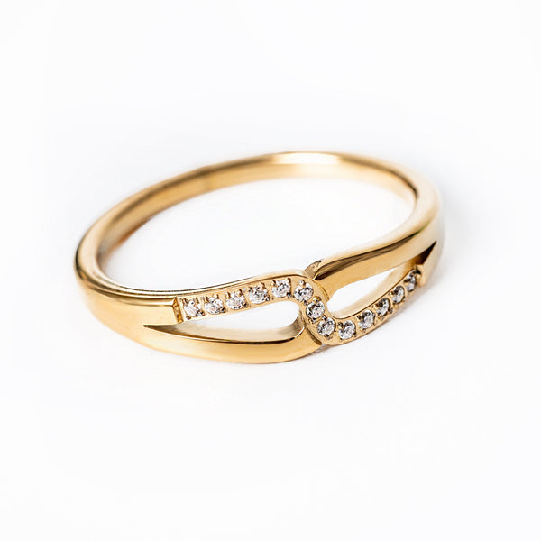 A gold-colored stainless steel  Marianne ring with a solid pattern and a small diamond-like stone set on top.