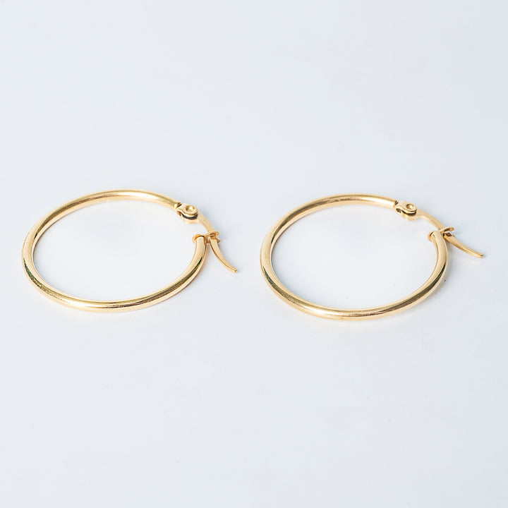 Gold Marlene hoop earrings with a smooth polished finish on a white background