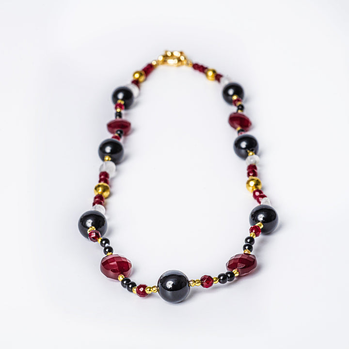 A maroon necklace with yellow gold plating and natural stone accents.