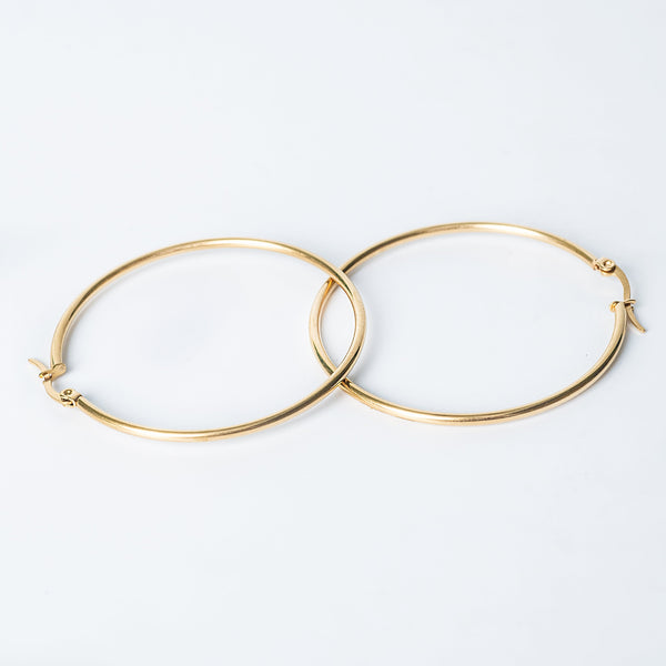 Gold Marthese hoop earrings with a smooth polished finish shown overlapping on a white background