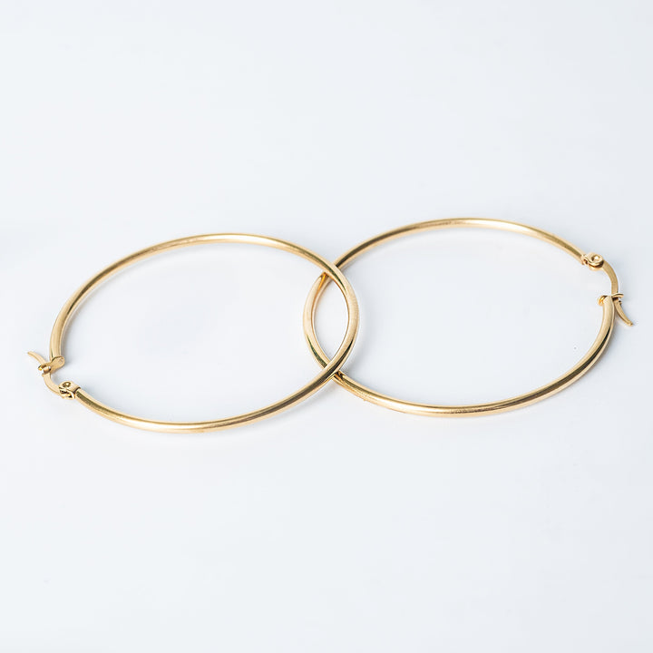 Gold Marthese hoop earrings with a smooth polished finish shown overlapping on a white background