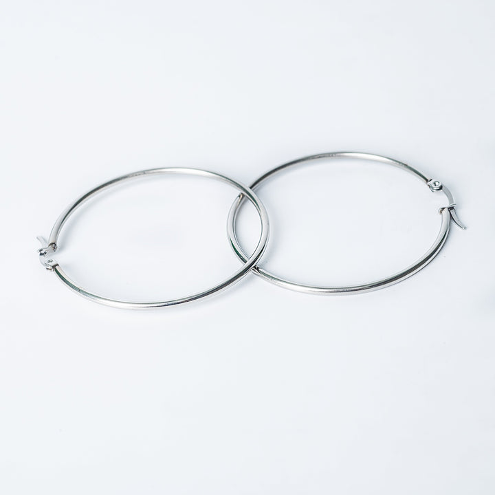 Silver Marthese hoop earrings with a smooth polished finish shown overlapping on a white background