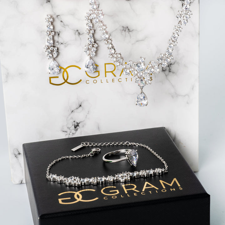 Melissa Earrings with necklace,ring, and bracelet set placed on their white and black boxes. 