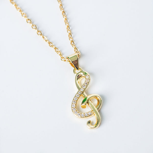 Gold treble clef pendant necklace with small clear crystals on a fine chain