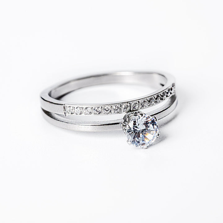 A silver-colored ring with a gold plated band and a central cubic zirconia gemstone.