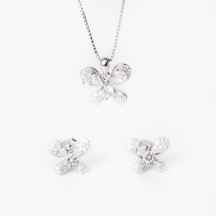 A sterling silver jewelry set including a pendant in the shape of a butterfly with cubic zirconia embellishments, a chain, and a pair of earrings, all laid out on a white surface.