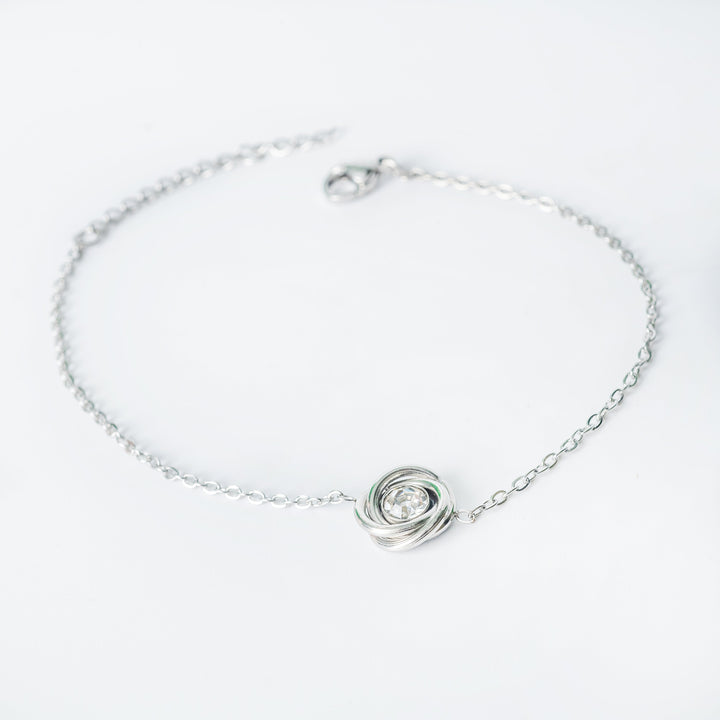 Silver chain bracelet with a central knot-style pendant featuring a clear round crystal
