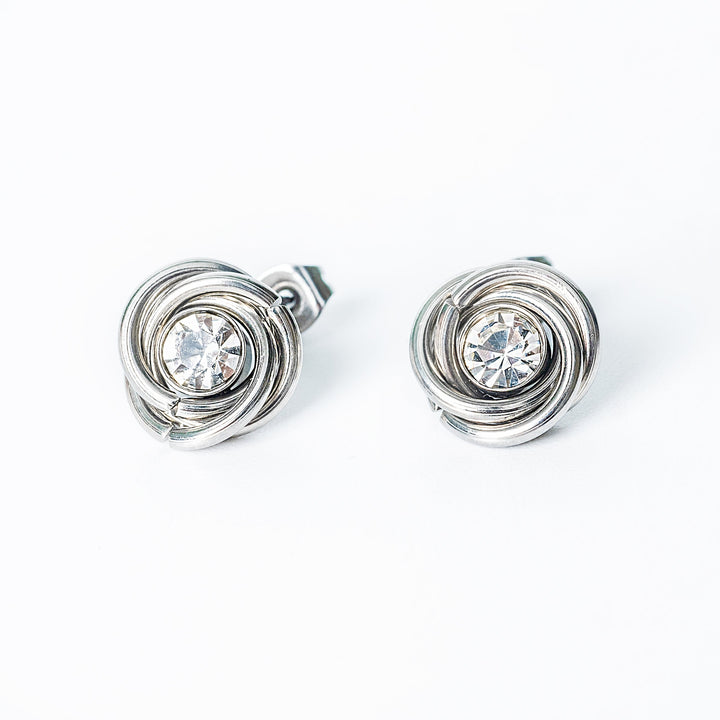 Silver knot-style stud earrings with round clear crystals in the center