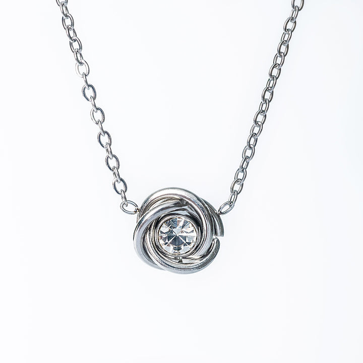 Silver knot-style necklace pendant with a clear round crystal in the center