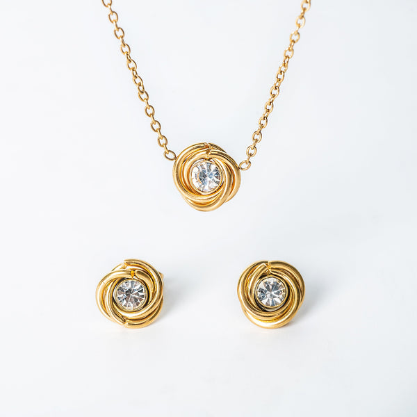 Gold jewelry set featuring a knot-style necklace and matching stud earrings with clear round crystals
