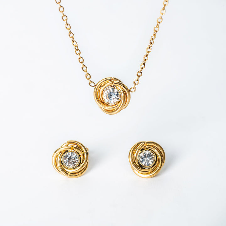 Gold jewelry set featuring a knot-style necklace and matching stud earrings with clear round crystals