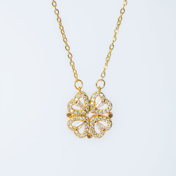 Gold Mira necklace featuring a four-leaf clover pendant made of heart-shaped elements with clear gemstones.