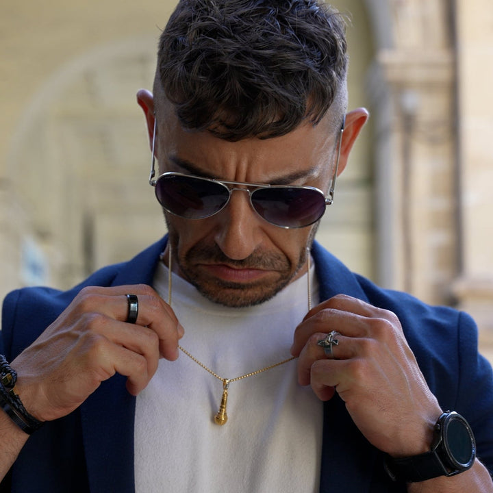 a man waring his singer necklace combined with blue suit and white shirt. 