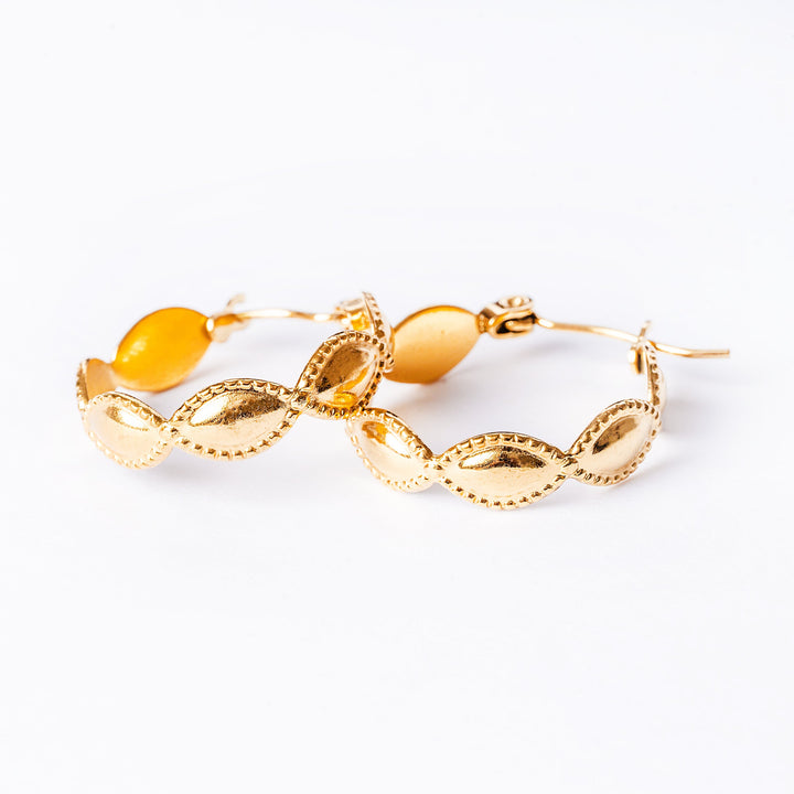 A close up view of Nakita Gold Earrings standing in the center of the image against a white background. 