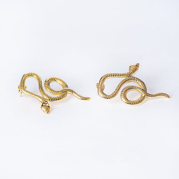 A pair of gold-plated stainless steel Nixi earrings designed to resemble a snake, displayed against a white background.