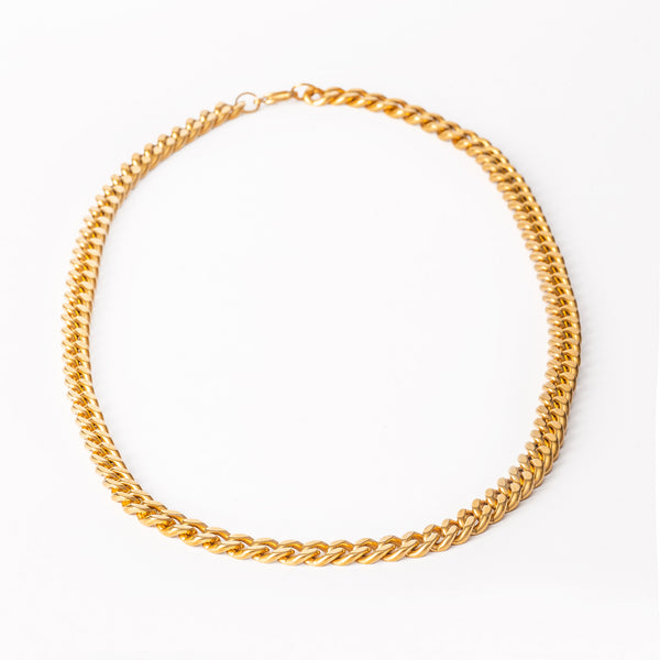 A close up view of yellow gold stainless steel bracelet with a loop closure on a white background.