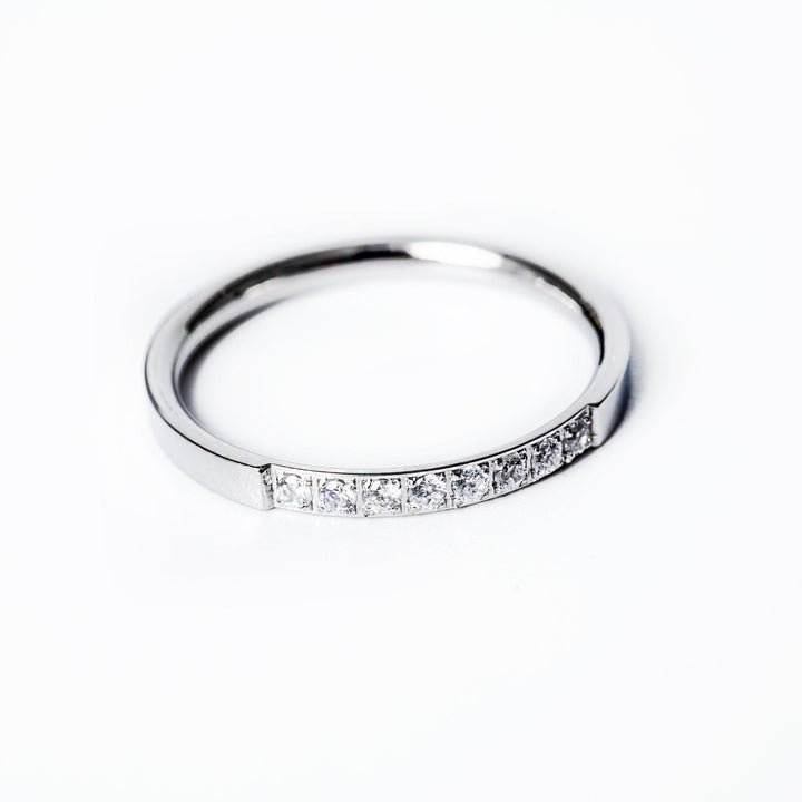 A silver-colored stainless steel ring Paula with a gold plated band, featuring a row of AAA cubic zirconia gems set around its circumference.