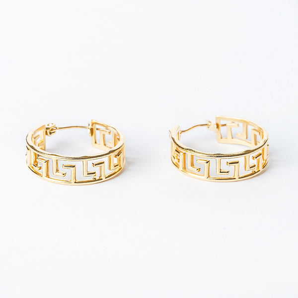 A pair of yellow gold hoop earrings with a geometric pattern, displayed against a white background.