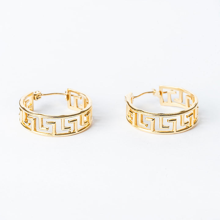 A pair of yellow gold hoop earrings with a geometric pattern, displayed against a white background.
