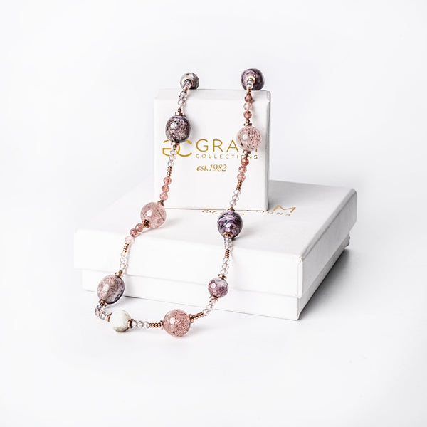 A silver-colored necklace with gold-plated accents and natural stone beads, displayed in front of a white box with 'Eclectic' brand visible.