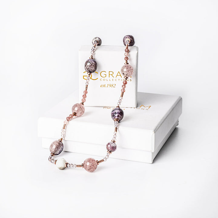 A silver-colored necklace with gold-plated accents and natural stone beads, displayed in front of a white box with 'Eclectic' brand visible.