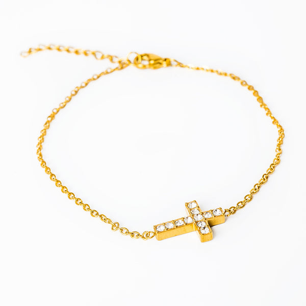 A gold-plated yellow bracelet featuring a cross-shaped cubic zirconia gemstone on a chain-linked design.