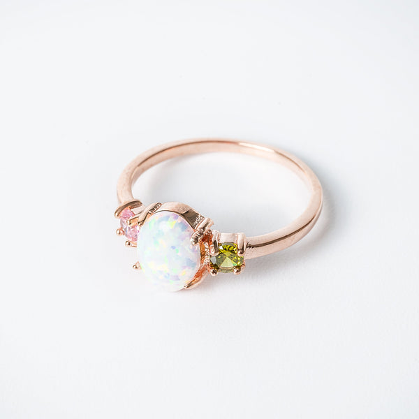 A rRen ring with a central multicolored cubic zirconia gemstone surrounded by smaller clear crystals.