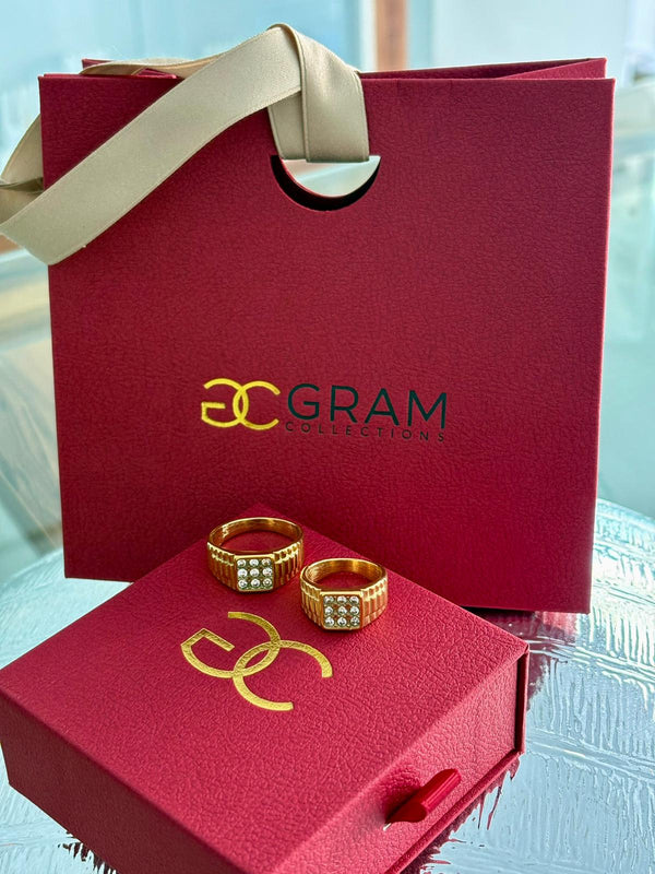 Two gold-colored Rolex rings with cubic zirconia stones on a red presentation box with '30 GRAM' branding.