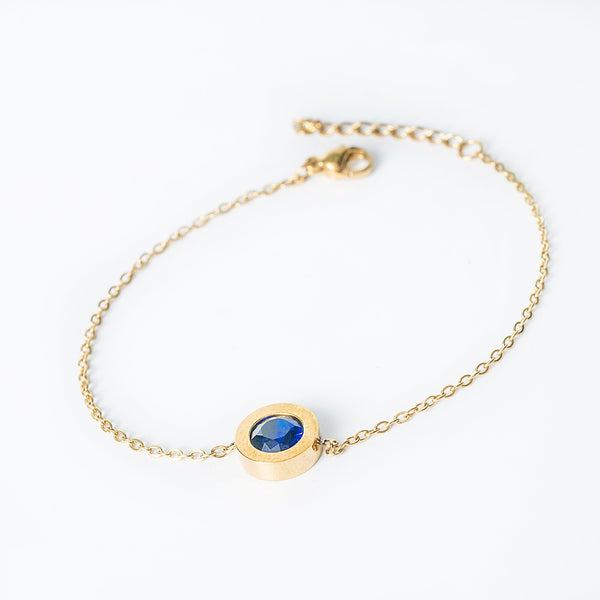 Gold Rosaria bracelet with a blue oval gemstone in a bezel setting