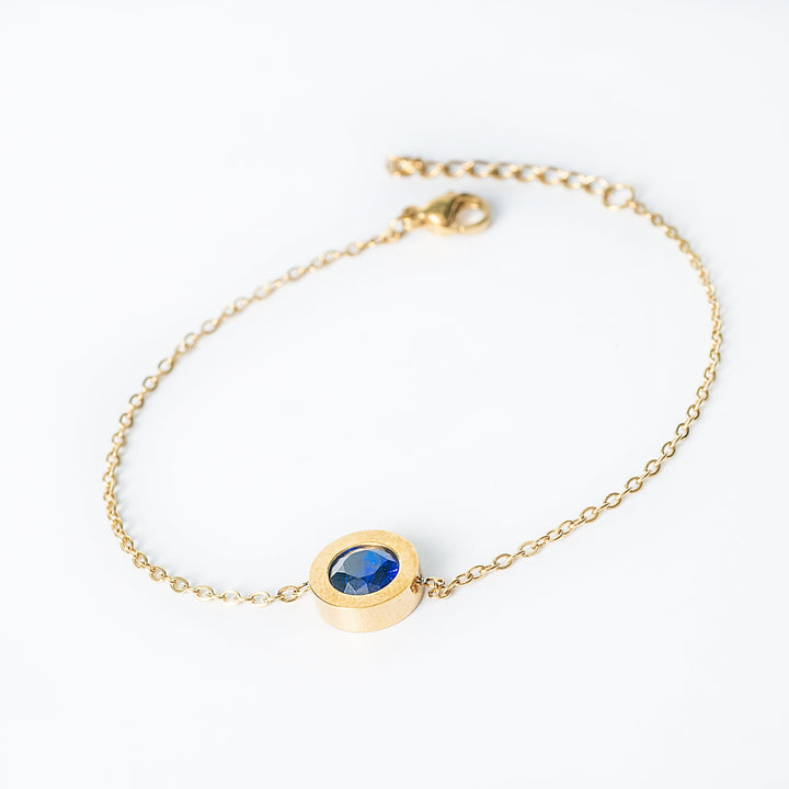 Gold Rosaria bracelet with a blue oval gemstone in a bezel setting