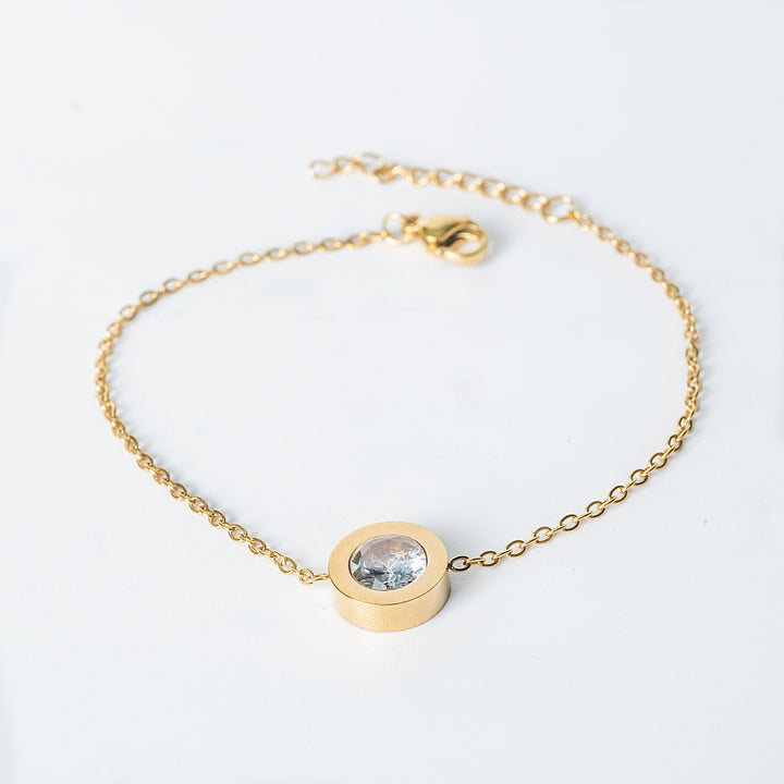 Gold Rosaria bracelet with a clear round gemstone in a bezel setting