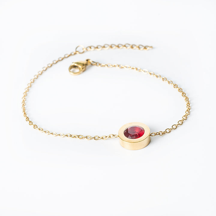Gold Rosaria bracelet with a red oval gemstone in a bezel setting
