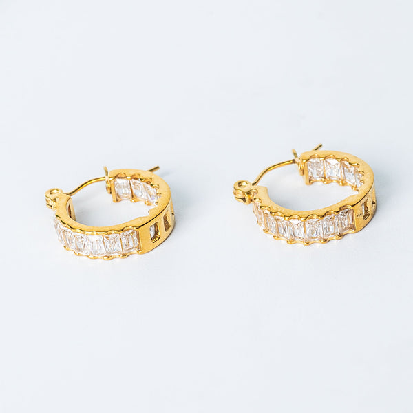 Gold Selena Earrings with rectangular clear gemstones arranged along the hoops.