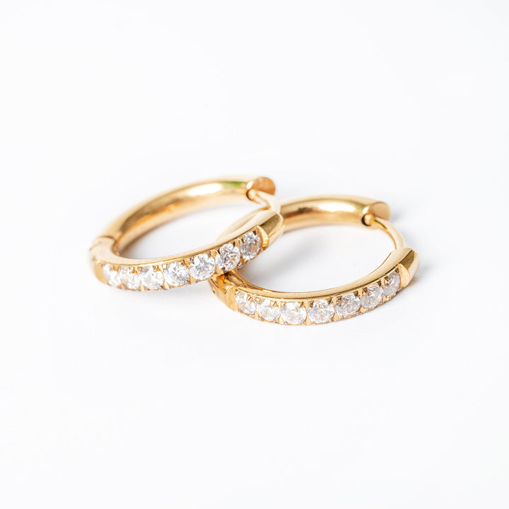 A close up view of Sharm Gold Earrings standing on top of each other against a white background. 