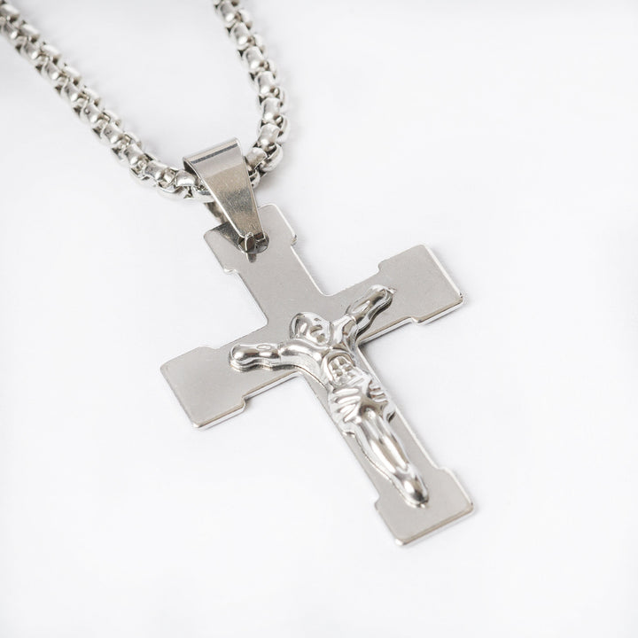 A close up view of Manly Cross Silver Necklace standing in the center of the image against a white background. 