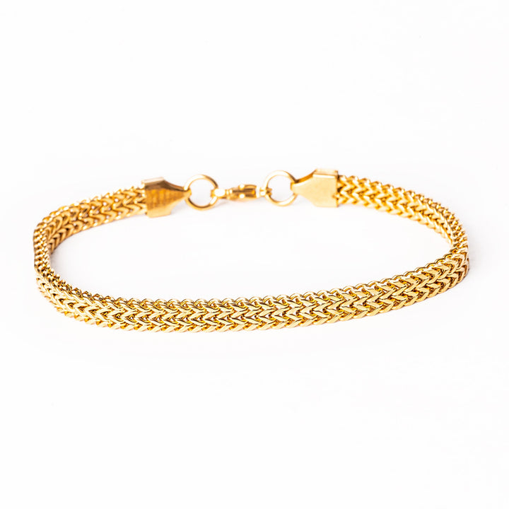 A yellow gold stainless steel bracelet with a solid pattern and a clasp closure.