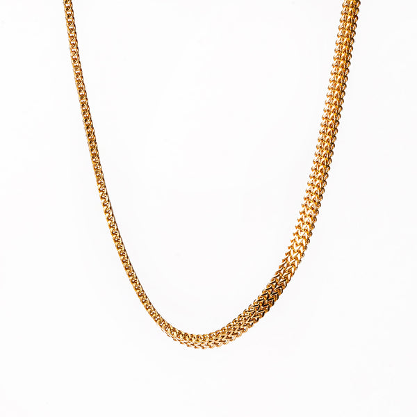 A sienna gold necklace chain standing in the center of the image against a white background. 