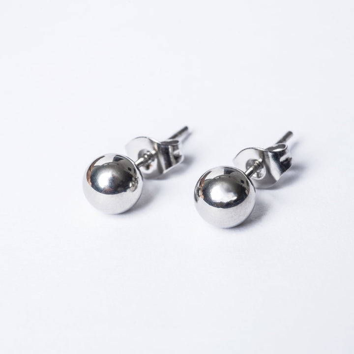 A close up view of silver Kim earring color, one placed from front, another from back part, standing in the center of the image against a white background. 