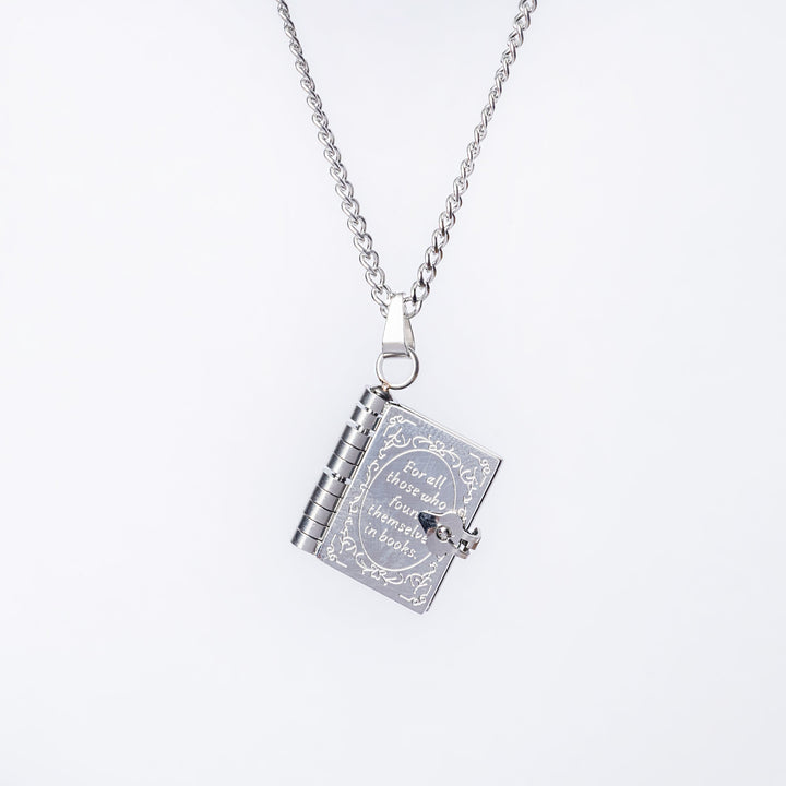The educational necklace standing in the center of the image against a white background, seeing from its. front side, with a text "For all those who found themselves in books". 