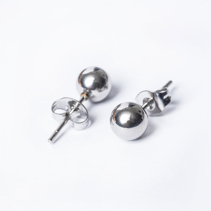 A close up view of silver kim earrings standing in the center of the image against a white background. 