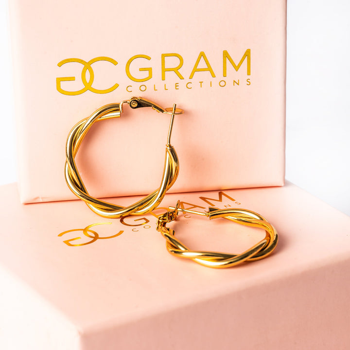 Solane earrings placed on its two beautifully designed pink boxex with a Gram Collection logo onto it. 