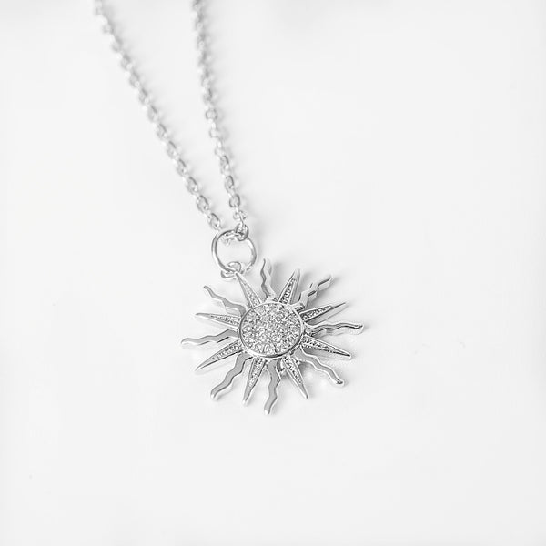 Silver sun-shaped pendant necklace with crystal detailing on a fine chain