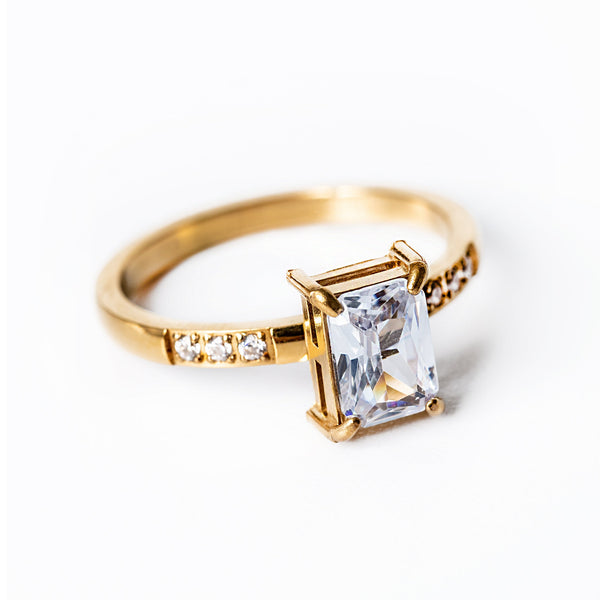 A gold-plated stainless steel ring with a yellow gold finish, featuring a clear, well-positioned cubic zirconia gemstone centerpiece.
